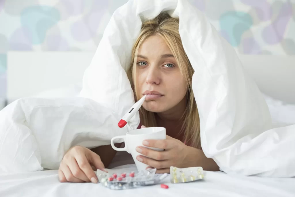 woman sick in bed flu thermomete